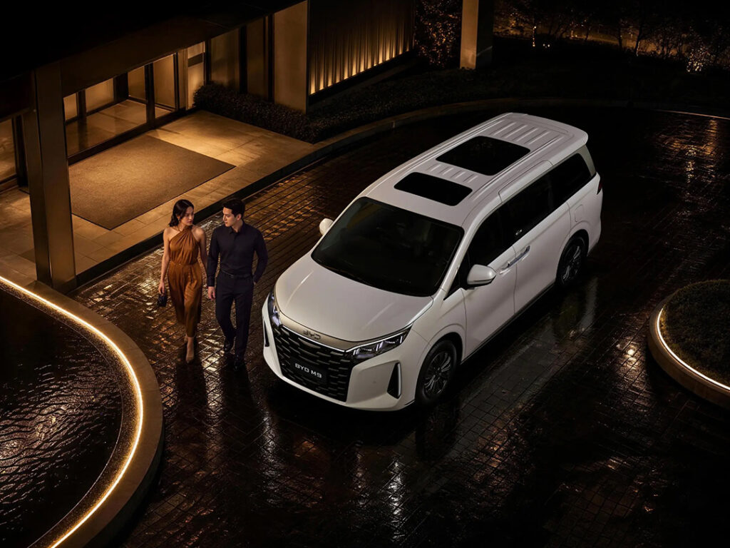 BYD M9 with family walking around it. High angle far away shot